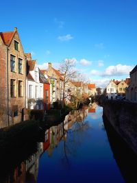 Canal amidst houses and buildings against sky