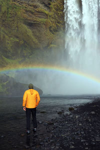 Rear view of man standing against waterfall