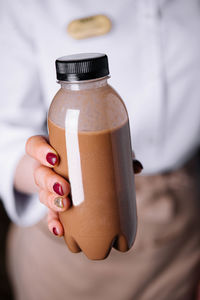 Midsection of woman holding bottle