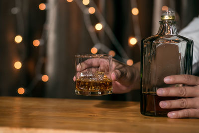 Midsection of person holding glass jar on table