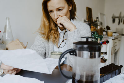 Female entrepreneur with paper document at table in living room