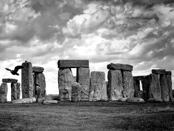 Stone structure on field against cloudy sky