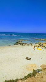 Scenic view of beach against clear blue sky