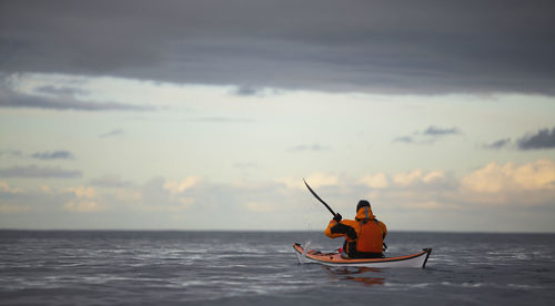 Mature man steering his sea kayak through calm waters around reykjavik