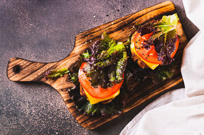 Close up of keto burgers on lettuce leaves from cutlet, tomatoes and cheese on a board top view