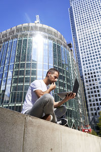 Man using laptop in city on sunny day