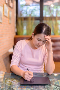 Young woman using mobile phone while sitting on table