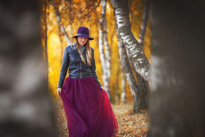 Woman wearing hat while standing in forest during autumn