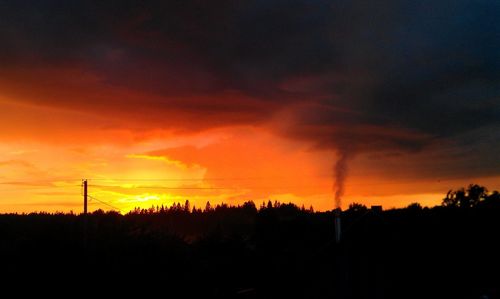 Low angle view of silhouette trees against dramatic sky