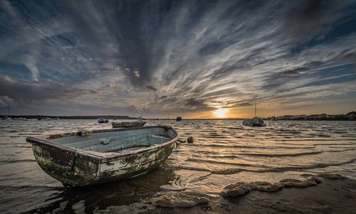 Panoramic view of boats on beach against cloudy sky
