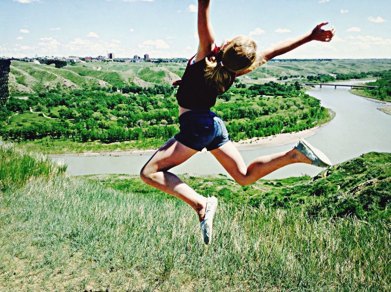 leisure activity, lifestyles, full length, grass, young adult, mid-air, jumping, enjoyment, tree, fun, carefree, young women, sky, casual clothing, arms raised, arms outstretched, person, freedom