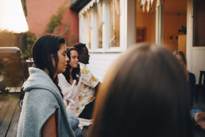 Multi-ethnic male and female friends sitting with eyes closed during group session at weekend