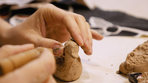 Cropped hands of craftsperson making clay product in pottery workshop