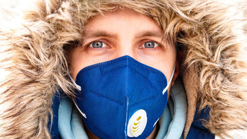 Close-up portrait of man wearing mask and warm clothing