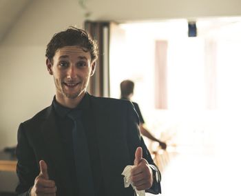 Portrait of smiling businessman gesturing thumbs up