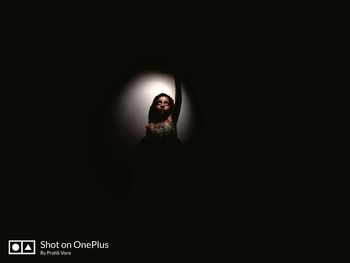 Midsection of woman standing against black background