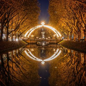 Illuminated bridge over canal in city at night