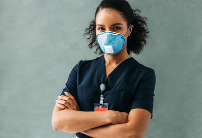 Portrait of young doctor standing against wall