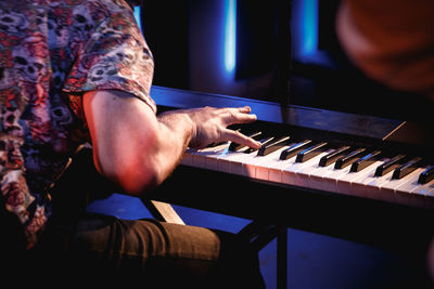 Midsection of man playing piano in recording studio