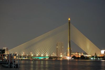 Illuminated bridge over river at night