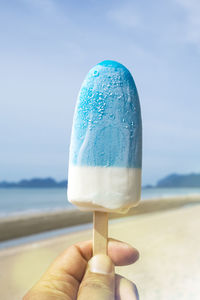 Close-up of hand holding ice cream on beach