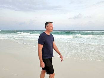 Single generation x man walking down beach in morning routine.