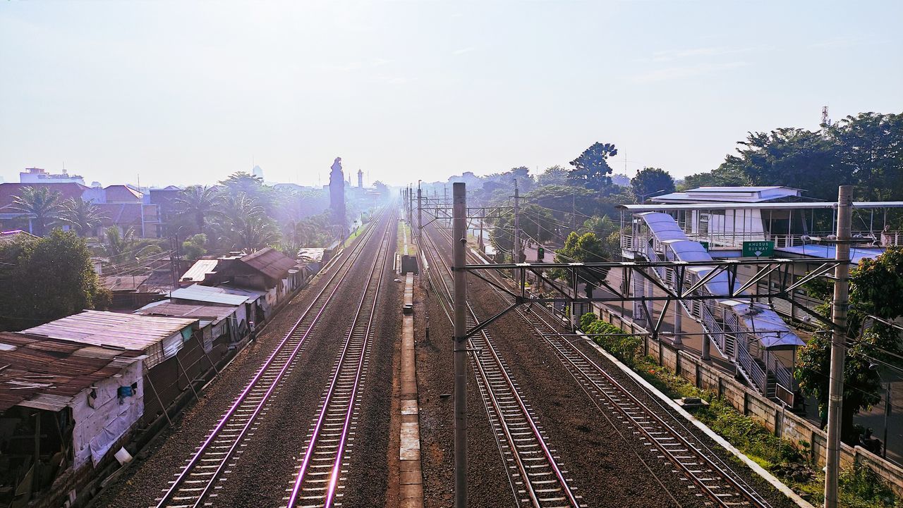 rail transportation, railroad track, track, architecture, transport, transportation, metropolitan area, sky, built structure, city, mode of transportation, railway, train, nature, building exterior, cityscape, railroad station, travel, public transportation, vehicle, rolling stock, public transport, high angle view, no people, travel destinations, building, outdoors, day, railroad station platform, urban area, train station, plant, tree, residential area, sunlight, landscape