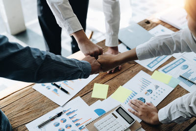 Midsection of business people shaking hands on table