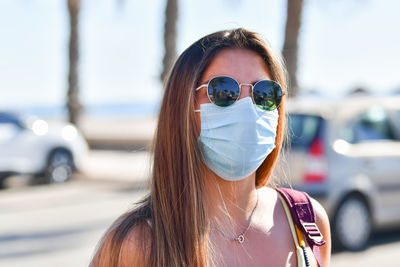 Portrait of young woman wearing sunglasses and mask