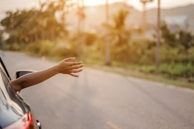 Cropped image of woman leaning hand out of car window