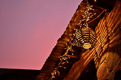 Low angle view of illuminated lantern and christmas lights outside house against clear sky