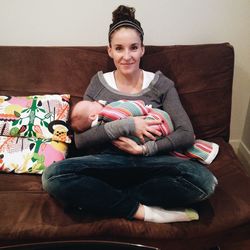 Full length portrait of smiling mother holding baby while sitting on sofa