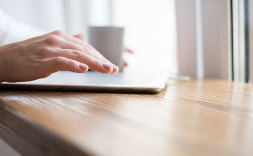 Close-up of man using laptop on table at home