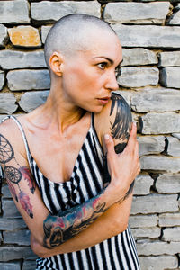 Portrait of woman standing against brick wall