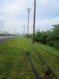 Railroad track amidst field against sky