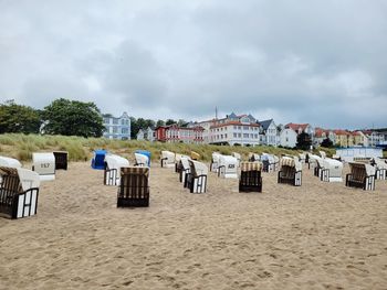 Hooded chairs on beach against sky