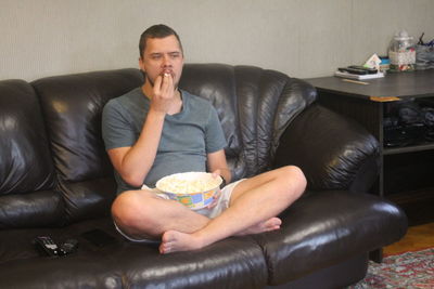 Full length of man sitting on sofa at home
