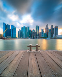 Sea by modern buildings against sky in city