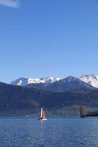 Sailboat in sea against clear blue sky