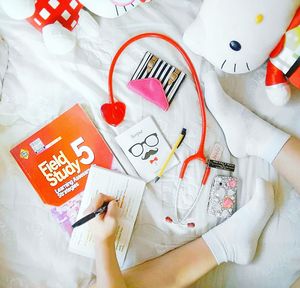 Low section of girl writing in book on bed at home