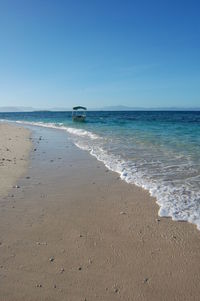 Scenic view of beach against clear blue sky