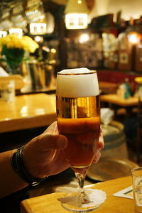 Cropped hand having beer in glass at bar