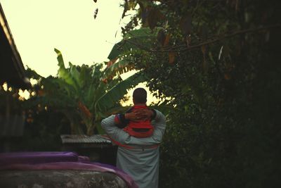 Rear view of father carrying son on shoulders during sunset