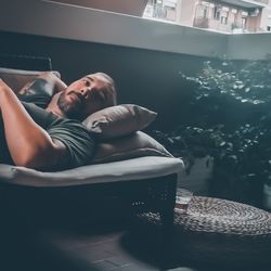 Thoughtful man lying on sofa in balcony