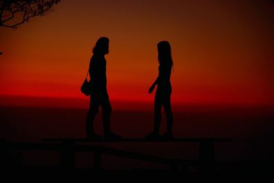 Silhouette people standing against sea during sunset