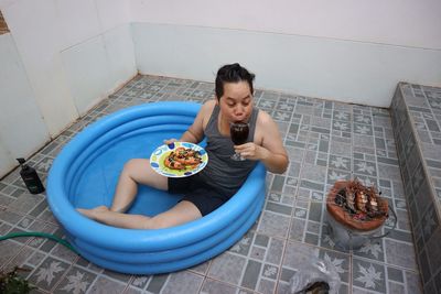 High angle view of woman having food while sitting in inflatable pool