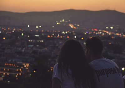 Rear view of couple against illuminated city at night