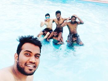 Portrait of young male friends enjoying in swimming pool