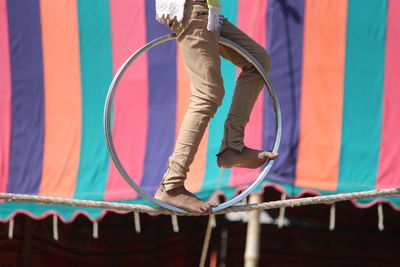 Low section of girl balancing wheel on tightrope