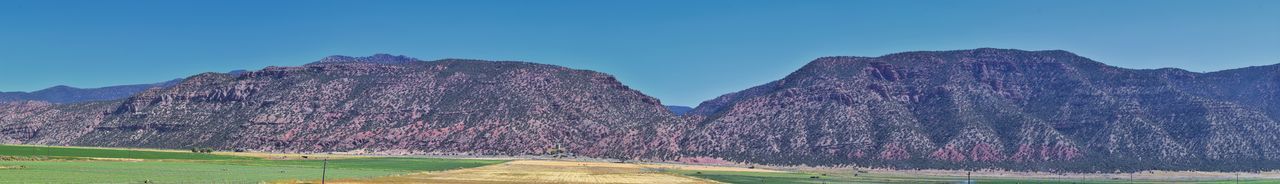 Panoramic view of rocky mountains against clear blue sky